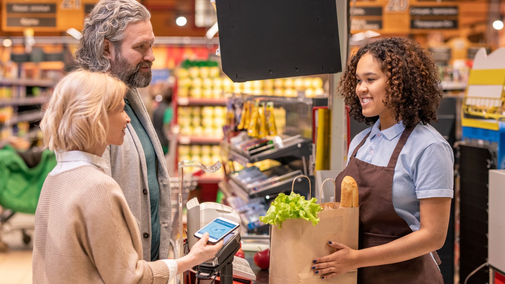 man and woman tapping to pay at grocery store checkout