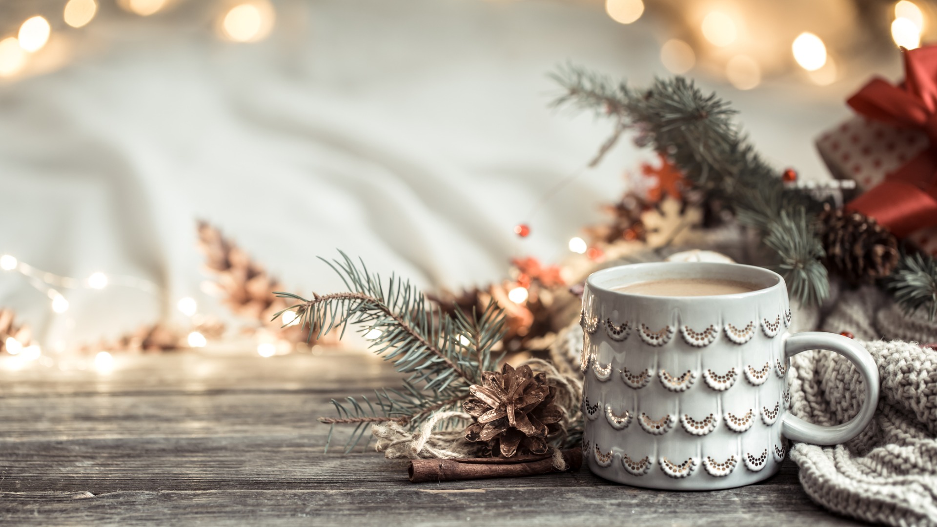 coffee cup in front of pine tree branches and pinecones